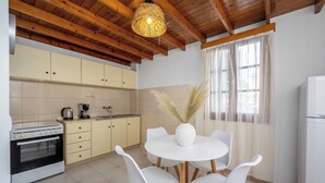Une cuisine avec des poutres en bois, un poêle, des placards, un évier et une table à manger avec des chaises.