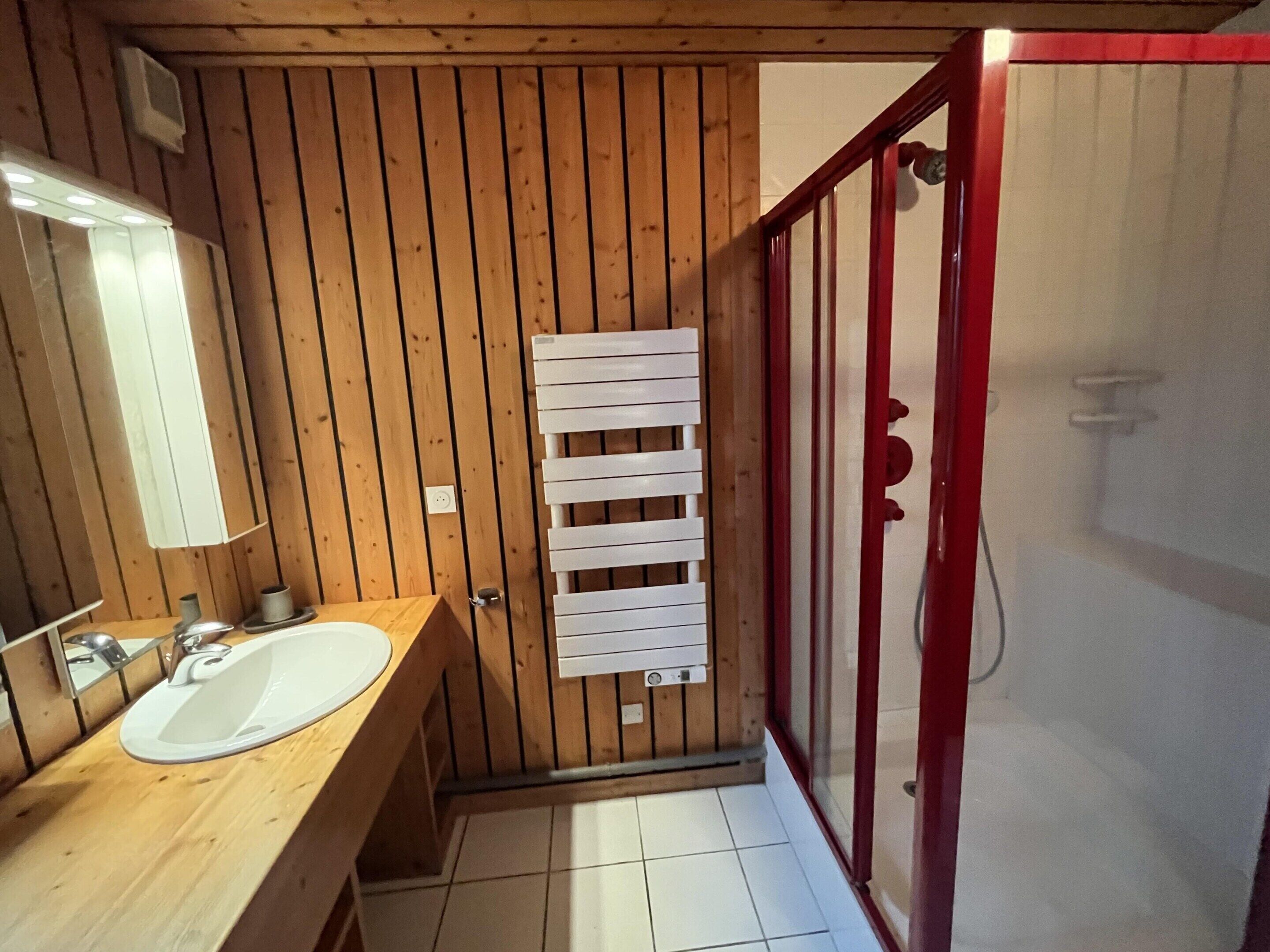 A wooden-paneled bathroom with a sink, mirror, and towel rack.