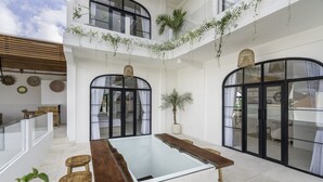 A spacious indoor area with a central glass table, wooden stools, and a potted plant.