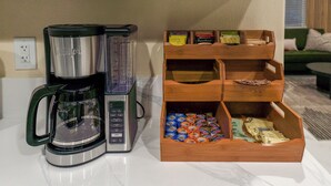 Une machine à café et une boîte en bois contenant des dosettes de café et des sachets de thé.