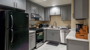Une cuisine moderne avec des meubles gris, des appareils en acier inoxydable et un sol en marbre.