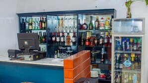 A bar area with a counter, shelves of liquor bottles, a computer, and a refrigerator. - Appleville Suites (Lagos)