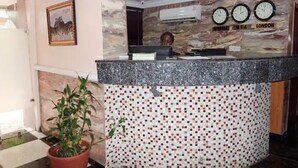 A reception area with a stone wall, a mosaic tile design, a clock, and a potted plant. - Appleville Suites (Lagos)