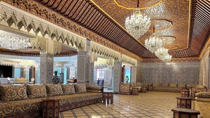 A spacious room with intricate tile work, a large sofa, and a chandelier. - Palais Bahida (marrakech)