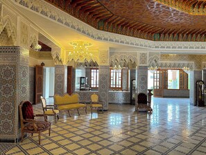 An opulent room with intricate tile work, a chandelier, and ornate furniture.
