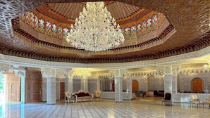 A spacious interior with intricate tile work, a large chandelier, and ornate wooden doors. - Palais Bahida (marrakech)