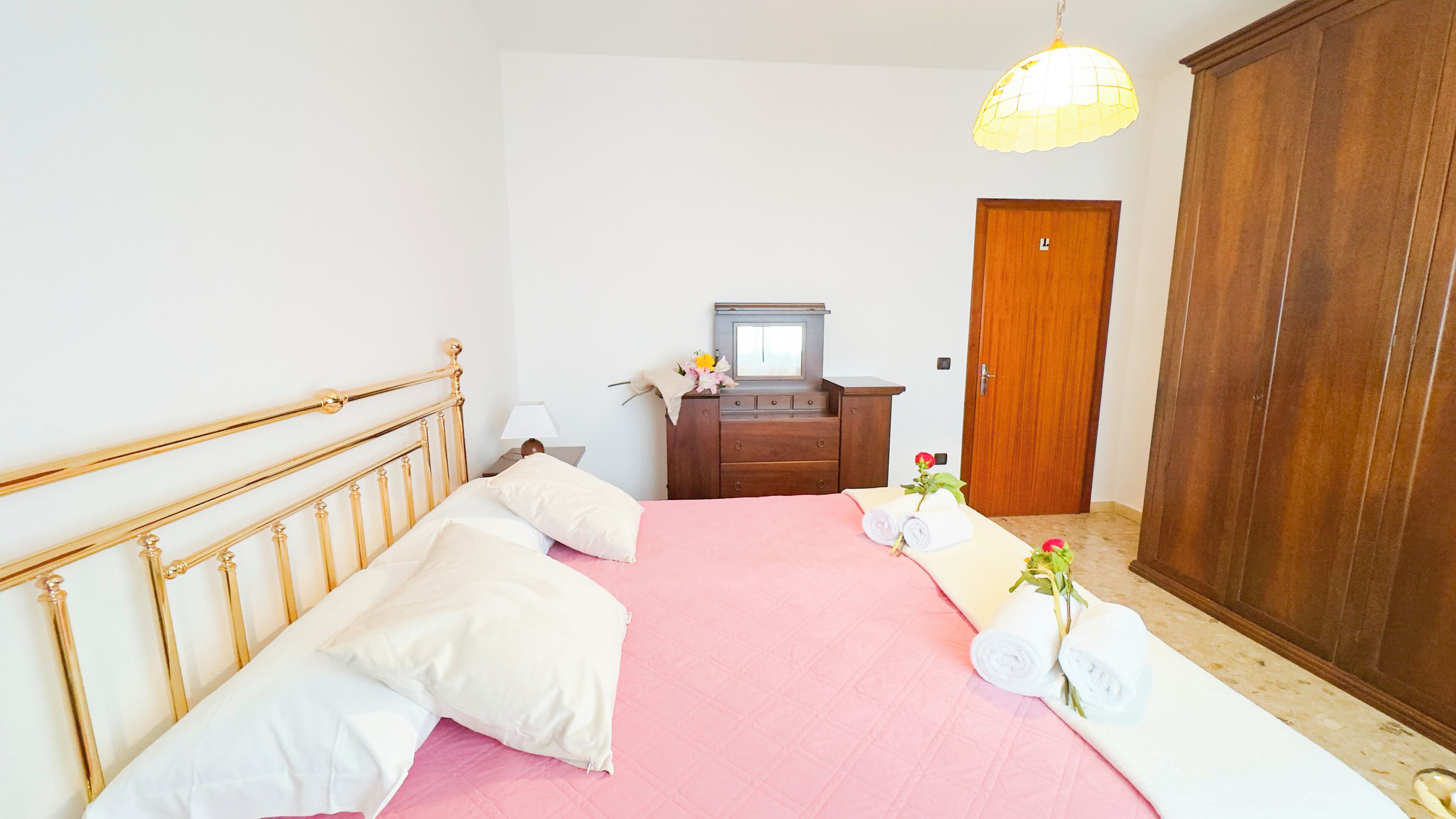 Un dormitorio con cama, armario de madera y escritorio con espejo.