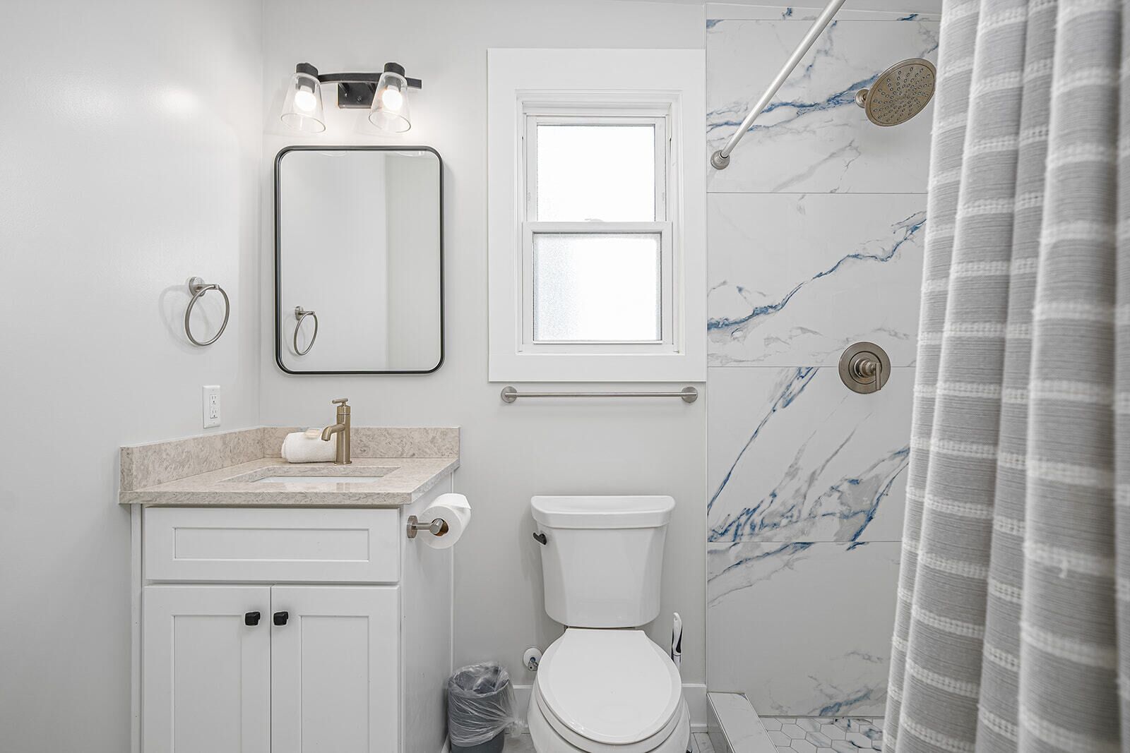Un bagno con toilette, lavandino, specchio e doccia.