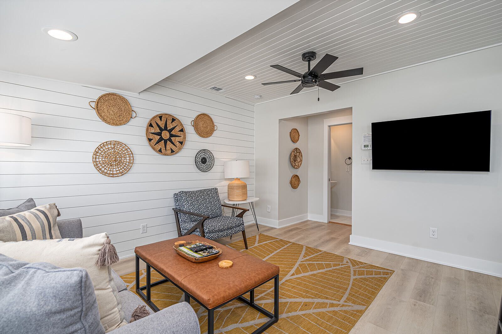 A living room with a sofa, armchair, coffee table, and decorative wall hangings.