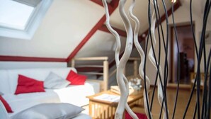 A cozy room with a bed, a white sofa, and a wooden table. - Cap sur le Sable at Port de Moguériec (Sibiril)