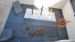 A rooftop terrace with a seating area, decorative spheres, and a spiral metal sculpture. - Cap sur le Sable at Port de Moguériec (Sibiril)