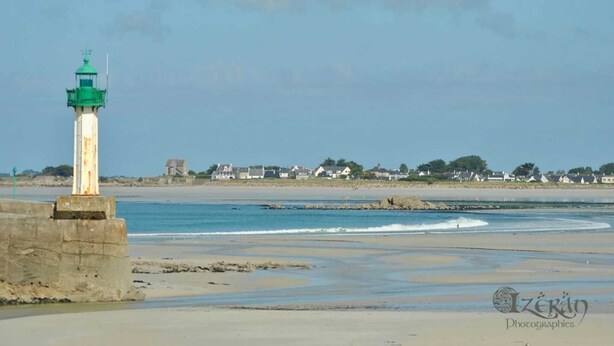 A lighthouse on a concrete base near a beach with houses in the background. - Cap sur le Sable at Port de Moguériec (Sibiril)