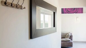 A modern interior with a large mirror, a coat rack, and a sofa in a well-lit hallway.