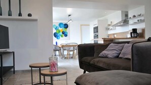 Een moderne woonkamer met een bank, een salontafel en een eethoek met stoelen en een tafel.