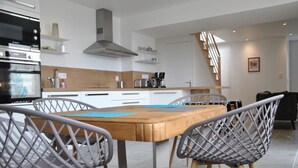 Een moderne keuken met witte kasten, een houten eettafel en twee stoelen.