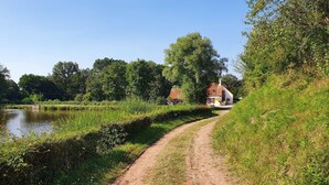 Une maison de campagne située près d’un étang, avec un chemin de terre qui y mène.