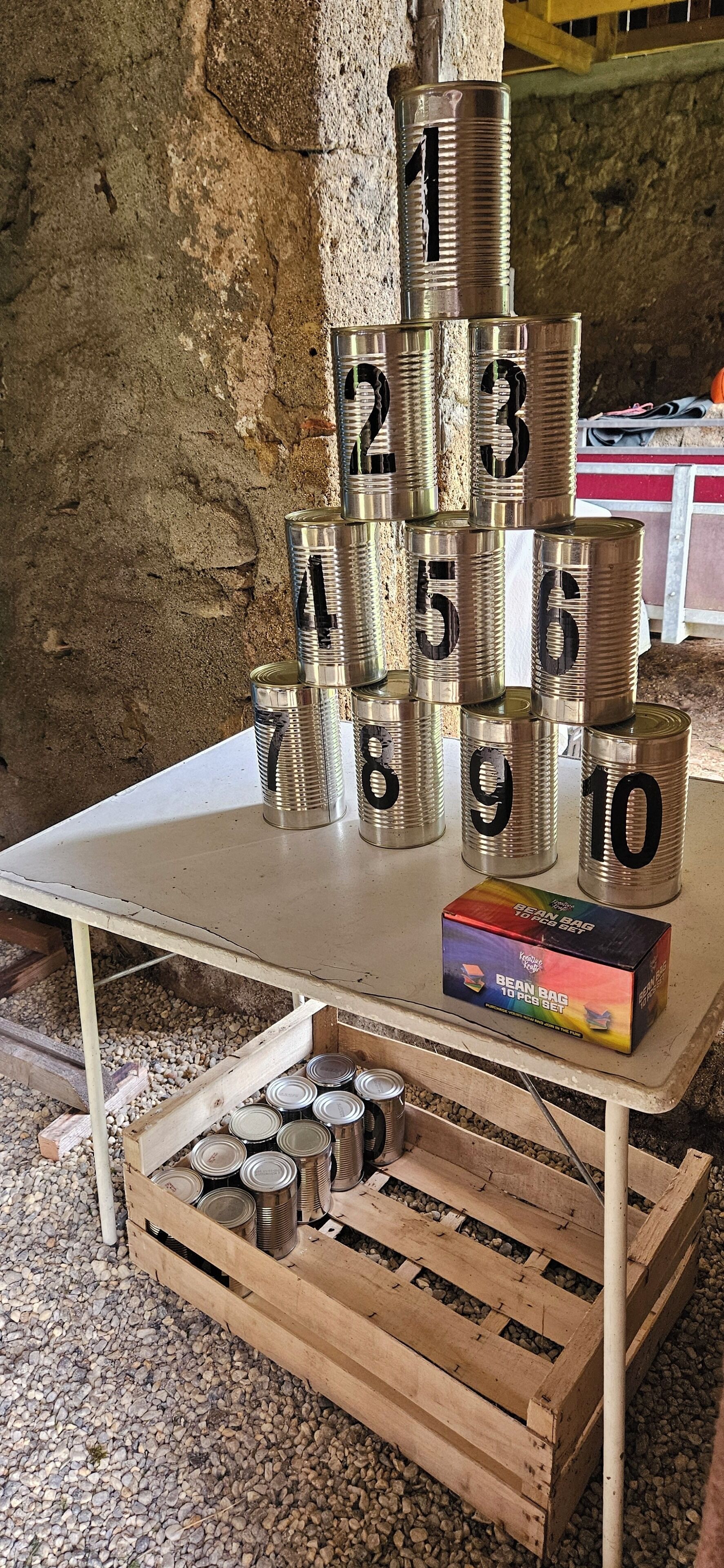 Une table sur laquelle sont empilées en pyramide des boîtes numérotées, un ensemble de sacs de haricots et une caisse en bois contenant d’autres boîtes.