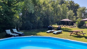 Une piscine extérieure équipée de chaises longues et de parasols.