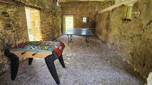 Une pièce dotée d’un baby-foot et d’une table de ping-pong, le tout dans un décor rustique aux murs de pierre.