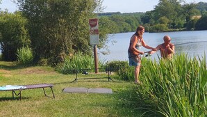 Deux personnes sont en train de pêcher au bord d’un lac, à proximité d’un panneau indiquant qu’il s’agit d’un endroit privé.