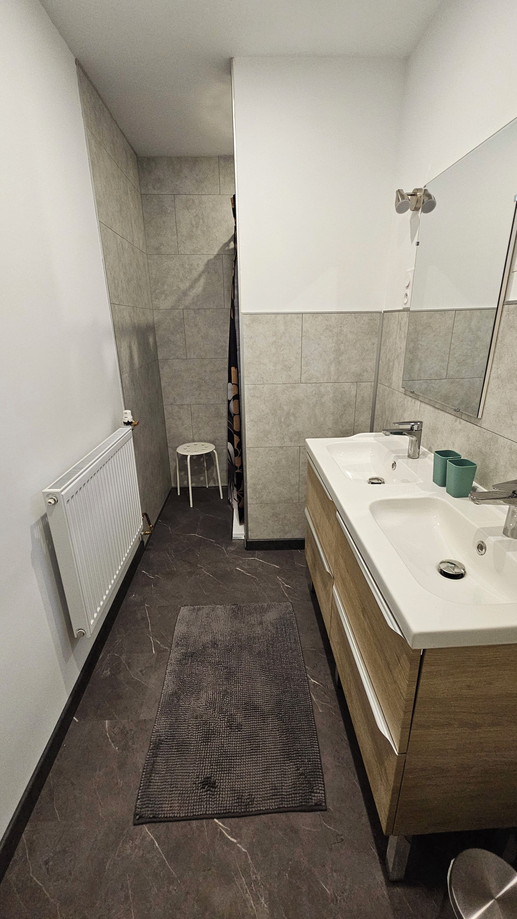 A modern bathroom with a white sink, a mirror, and a shower.