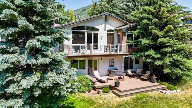 A two-story house with a balcony, outdoor seating area, and a well-maintained garden. - Gore Creek Alpine Chalet (Vail)