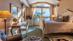 A bedroom with a large bed, a desk, a chair, and a window with curtains. - Gore Creek Alpine Chalet (Vail)