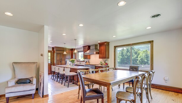 A spacious kitchen with wooden cabinets, a large dining table, and a comfortable seating area. - 3 Mi to Colgate Lake: Mtn-view Home, Deck + Grill! (East Jewett)