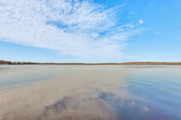 A calm lake with a clear sky and a distant shoreline.