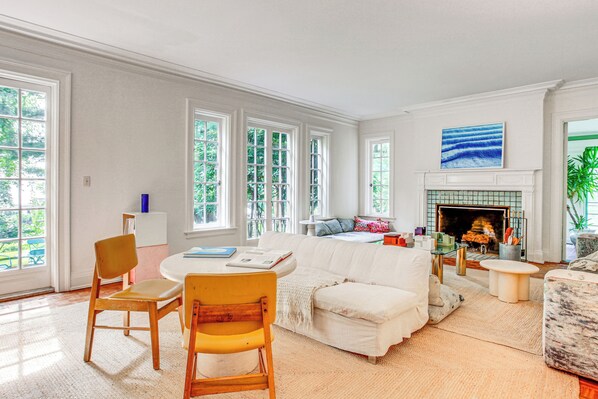A spacious living room with a white fireplace, large windows, and a cozy seating area. - Hudson Valley Estate on 4 Acres w/ Private Pool! (Nyack)