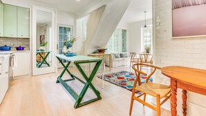 A spacious kitchen with wooden flooring, a dining area with a wooden table and chairs, and a large window providing natural light. - Hudson Valley Estate on 4 Acres w/ Private Pool! (Nyack)