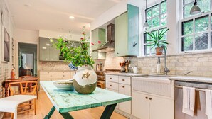 A kitchen with wooden cabinets, a marble countertop, and a large window with a view of trees. - Hudson Valley Estate on 4 Acres w/ Private Pool! (Nyack)