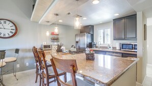 A modern kitchen with a large island, stainless steel appliances, and pendant lighting. - Games, Grill & Golf Course View: Palm Desert Gem! (Palm Desert)