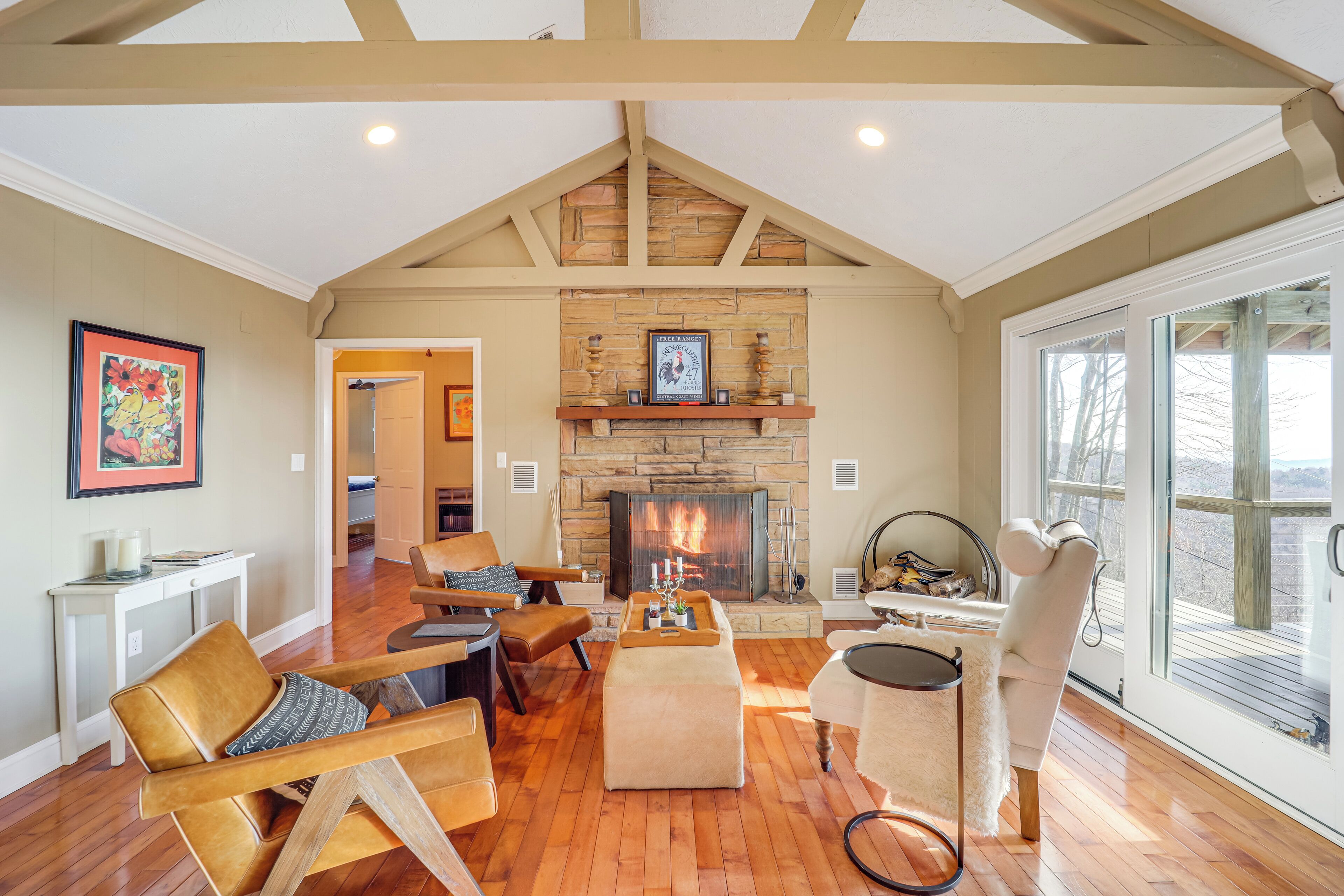 A spacious living room with a fireplace, wooden flooring, and a large window.
