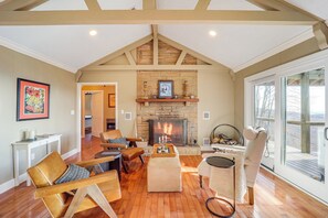 Een ruime woonkamer met een open haard, houten vloeren en een groot raam.