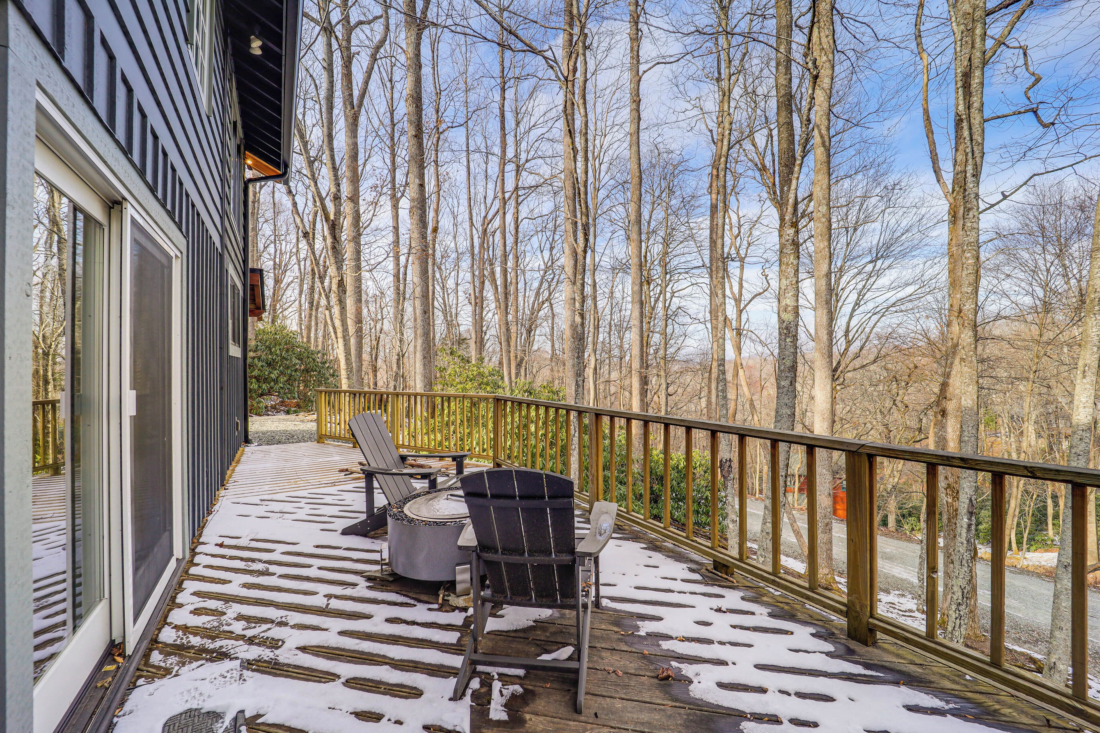 A covered deck with outdoor seating and a view of a forest.