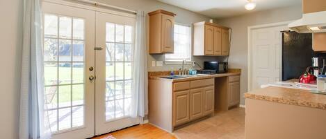 A kitchen with wooden cabinets, a granite countertop, and a black refrigerator.