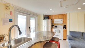 A compact kitchen with a granite countertop, stainless steel sink, and wooden cabinets. - Detached Backyard Studio in Fort Lauderdale! (Fort Lauderdale)