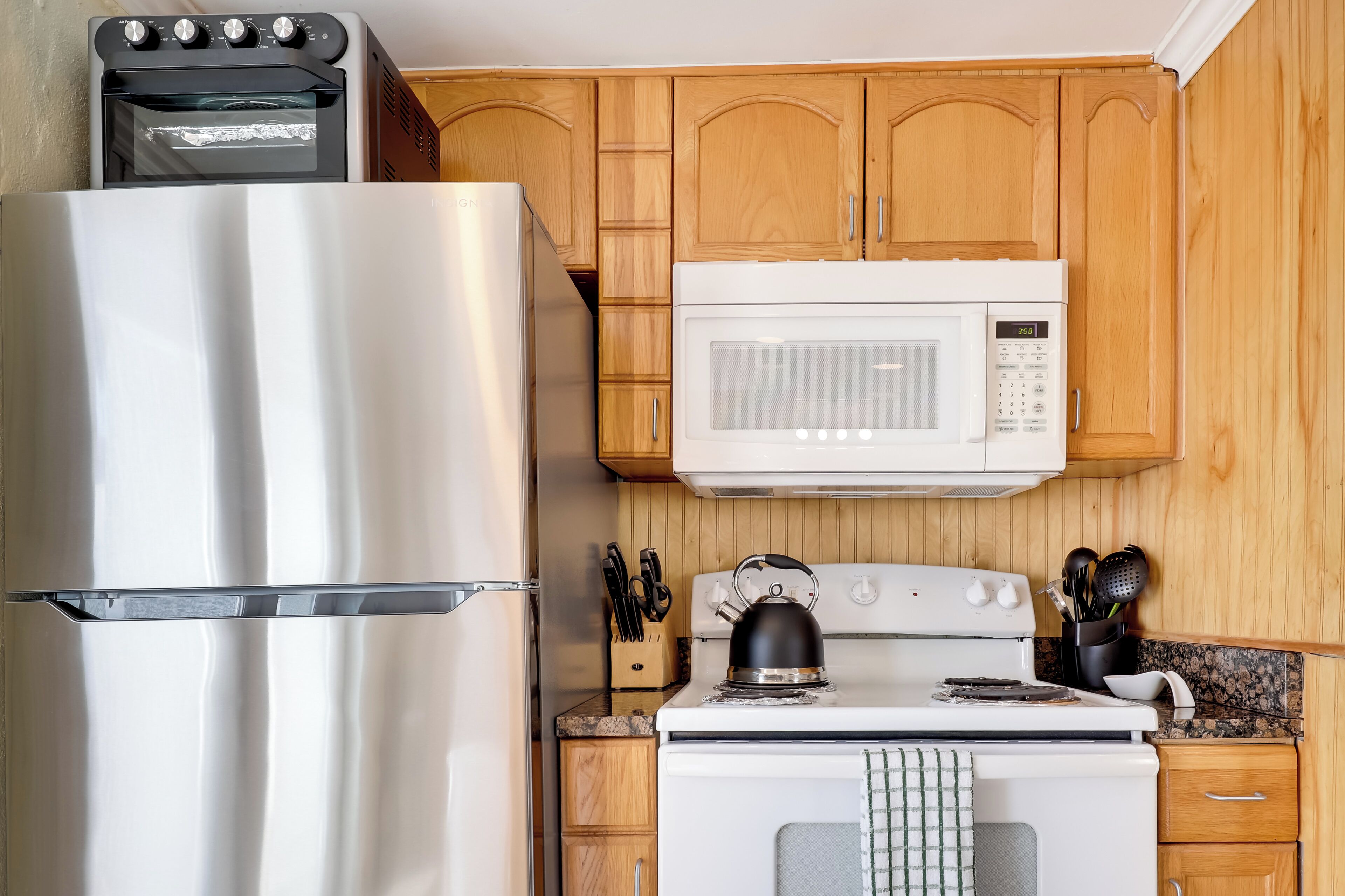 A kitchen with a stainless steel refrigerator, a microwave, and a stove.