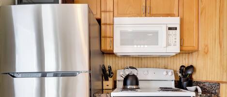 A kitchen with a stainless steel refrigerator, a microwave, and a stove.
