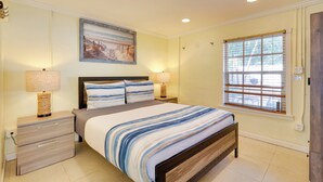 A bedroom with a bed, bedside tables, a painting, and a window with blinds. - Detached Backyard Studio in Fort Lauderdale! (Fort Lauderdale)
