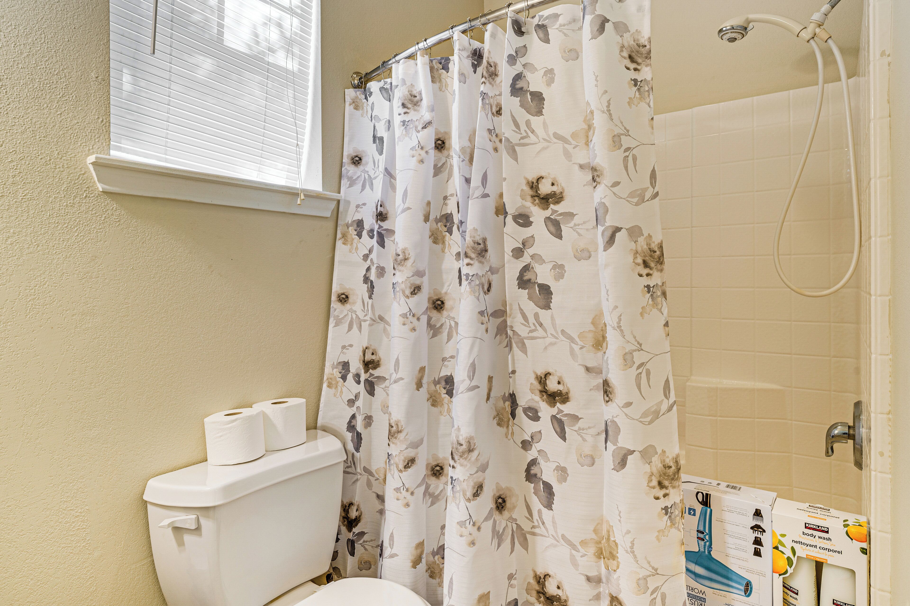 A bathroom with a toilet, a shower curtain, and a toilet paper holder.