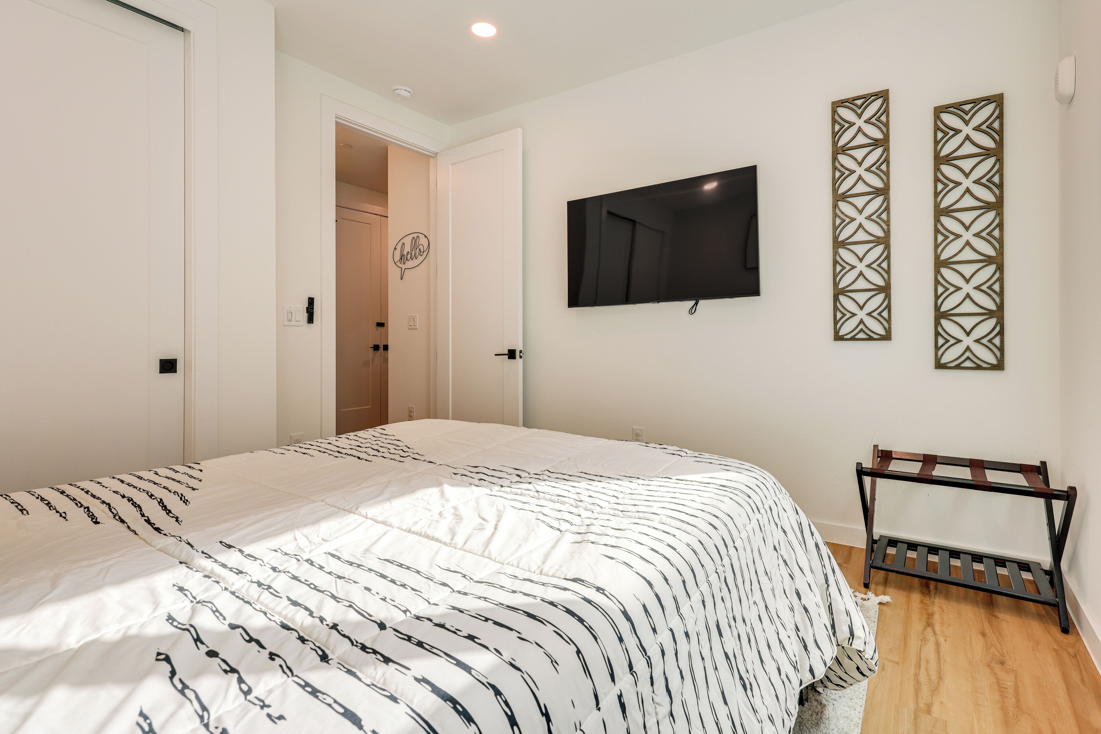 A bedroom with a bed, a TV mounted on the wall, and a wooden bench.