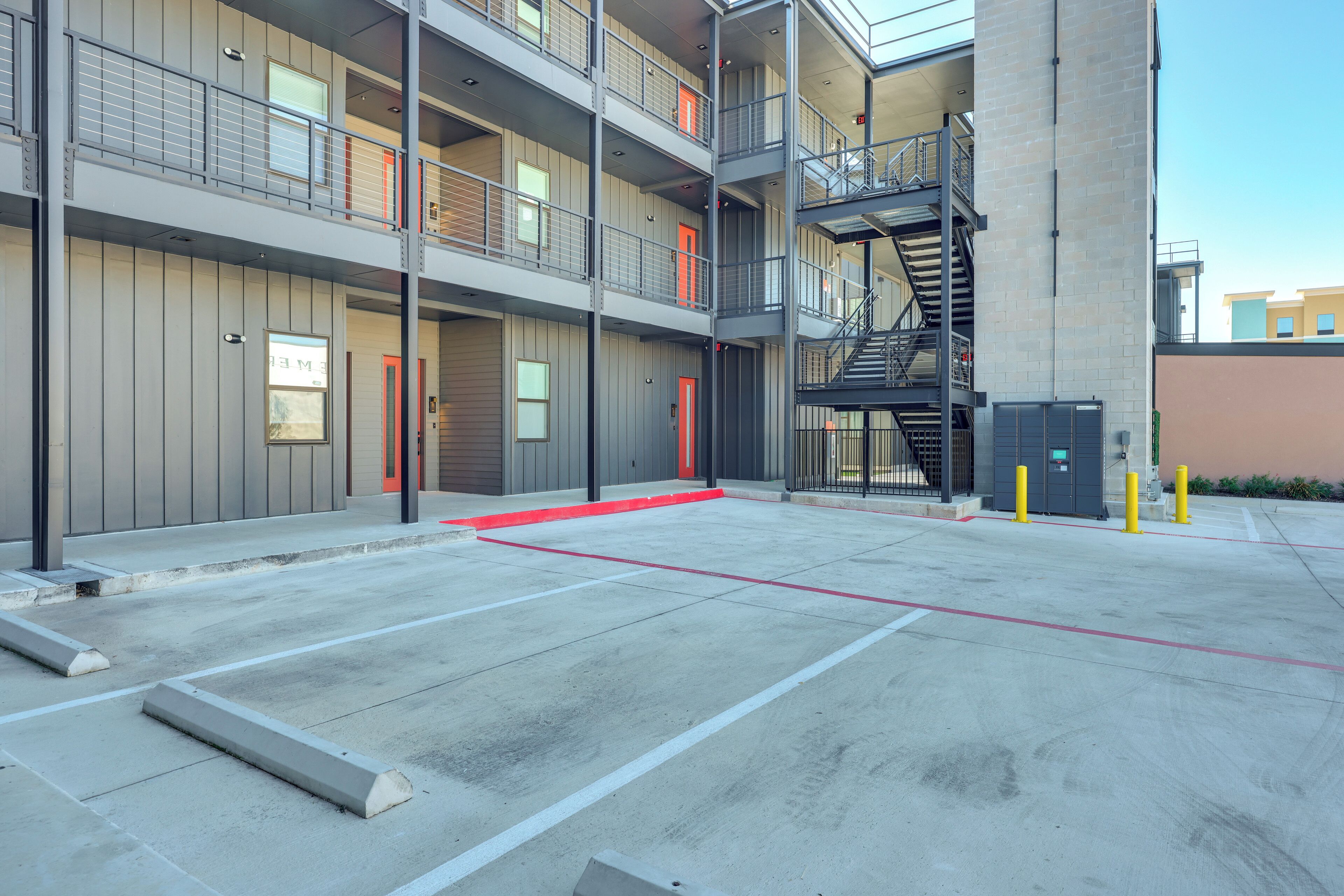 A multi-story building with a parking area, fire escape, and a visible fire hydrant.