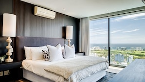 A modern hotel bedroom with a large bed, two bedside lamps, a view of the cityscape, and a large window. - Top Urban Escape w Pool and Ocean View Villa Alexa (Cape Town)