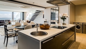 A modern kitchen with a central island, stainless steel sink, and a built-in oven. - Top Urban Escape w Pool and Ocean View Villa Alexa (Cape Town)