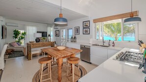 Una cocina moderna con una isla central, taburetes de bar y vistas al océano.