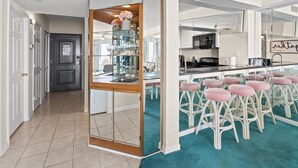 Uma cozinha moderna com uma ilha central, banquetas e um aparador de vidro.