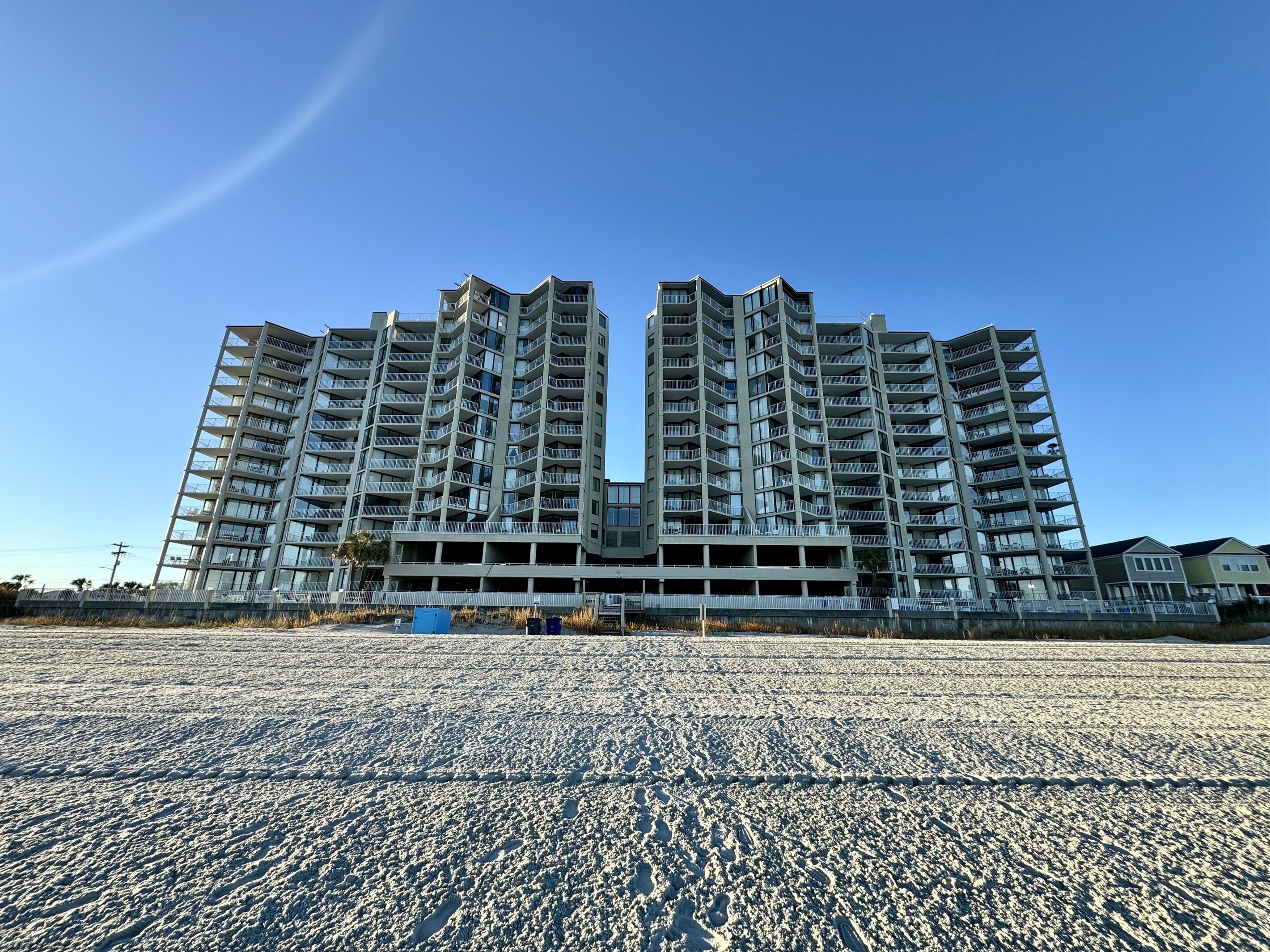 A high-rise residential building with multiple balconies and a parking structure below.