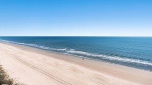 Uma praia extensa com céu claro.
